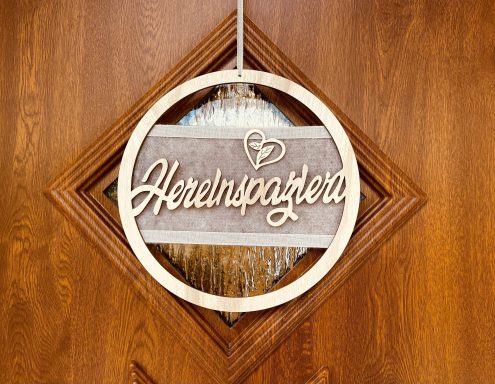 Wanddekoration aus Holz mit dem Schriftzug "Herzlich Willkommen" im Herzen.